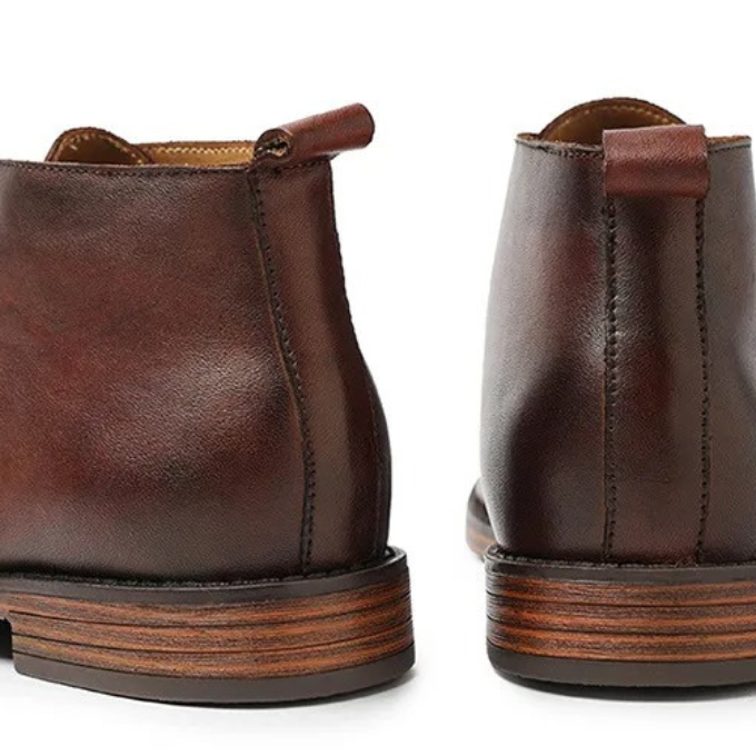 Men's leather boots stacked, showing different shades of brown and black options.