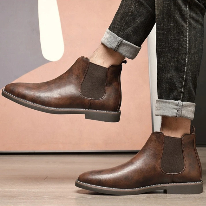Brown leather Chelsea boots for men, styled with cuffed jeans, modern footwear.