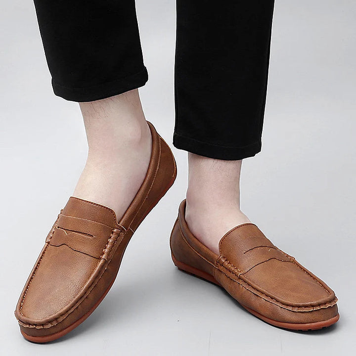 Close-up of a men's classic leather penny loafer, showcasing the detailed stitching.