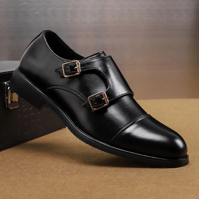 Close-up of men's leather double monk strap shoes showing two polished silver buckles on a rich brown background