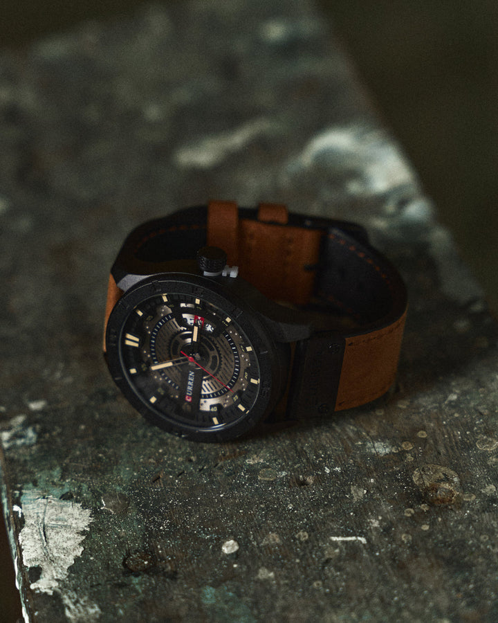 Close-up of men's analog watch, brown leather strap, silver casing, date window