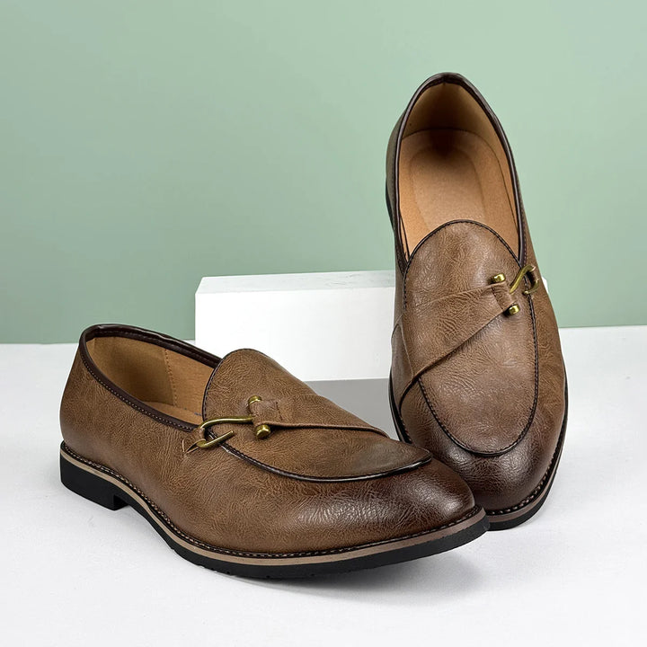 Detailed shot of the metal bit on a men's classic brown leather slip-on loafer.