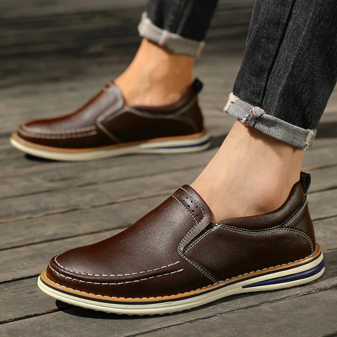 Group shot of multiple pairs of men's slip-on leather moc-toe loafers in a row.