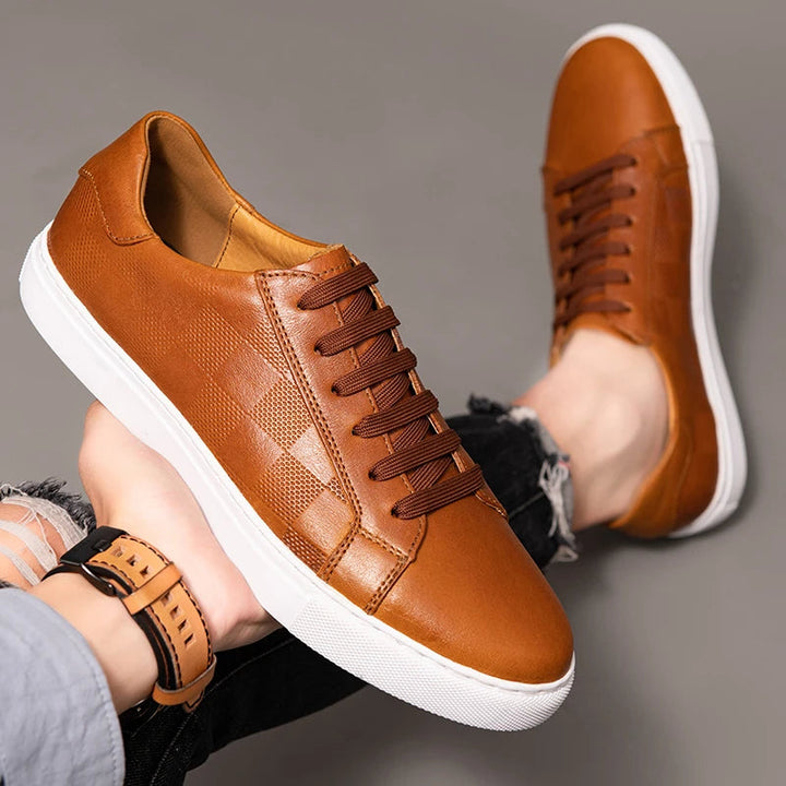 Men's grey leather low-top sneakers on a wooden floor, showcasing comfort-focused design for daily wear