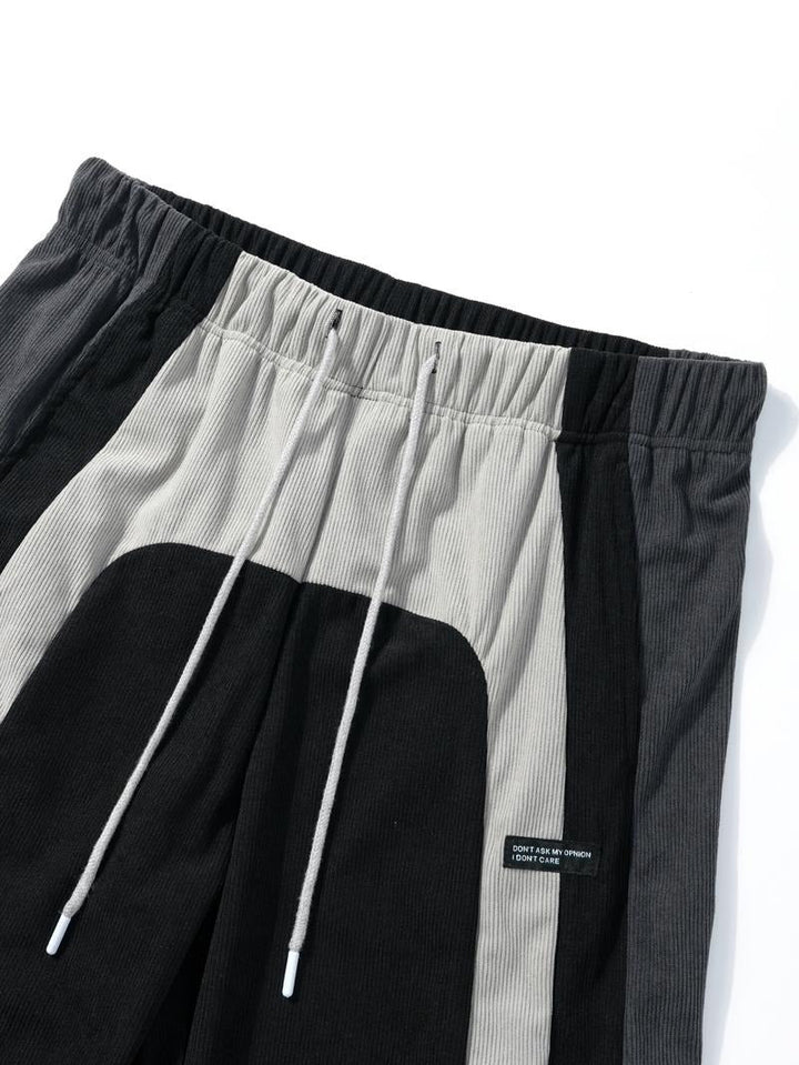 Men's corduroy track pants, color-block design, featuring elastic waist and tapered leg for streetwear look.