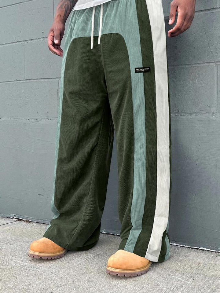 Close-up of men's corduroy track pants, showcasing unique color-block pattern and soft fabric texture.