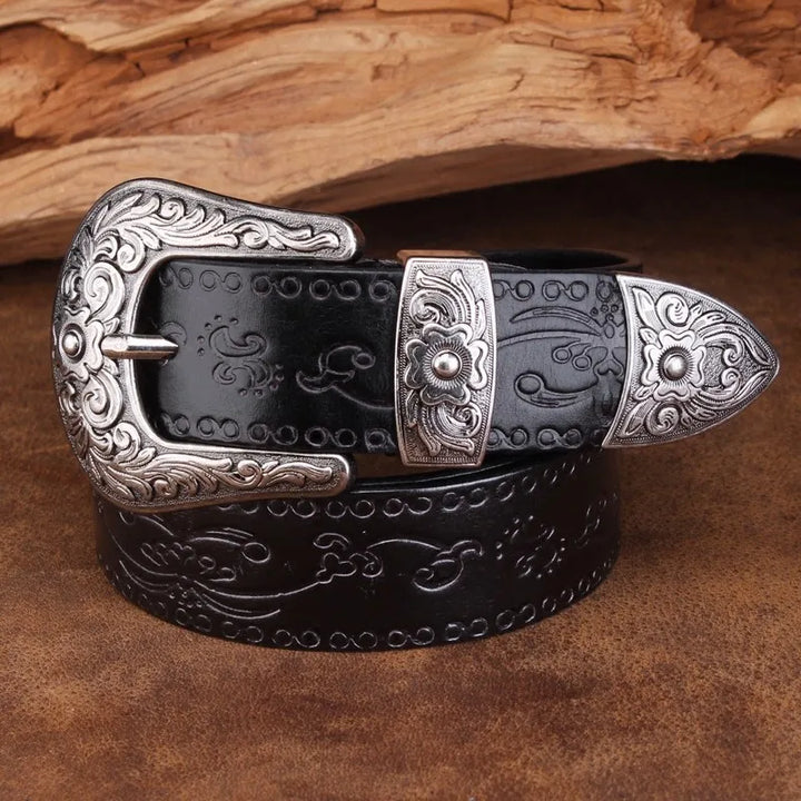 Close-up of a men's western belt showcasing fine floral scroll engraving on leather and a polished metal buckle.