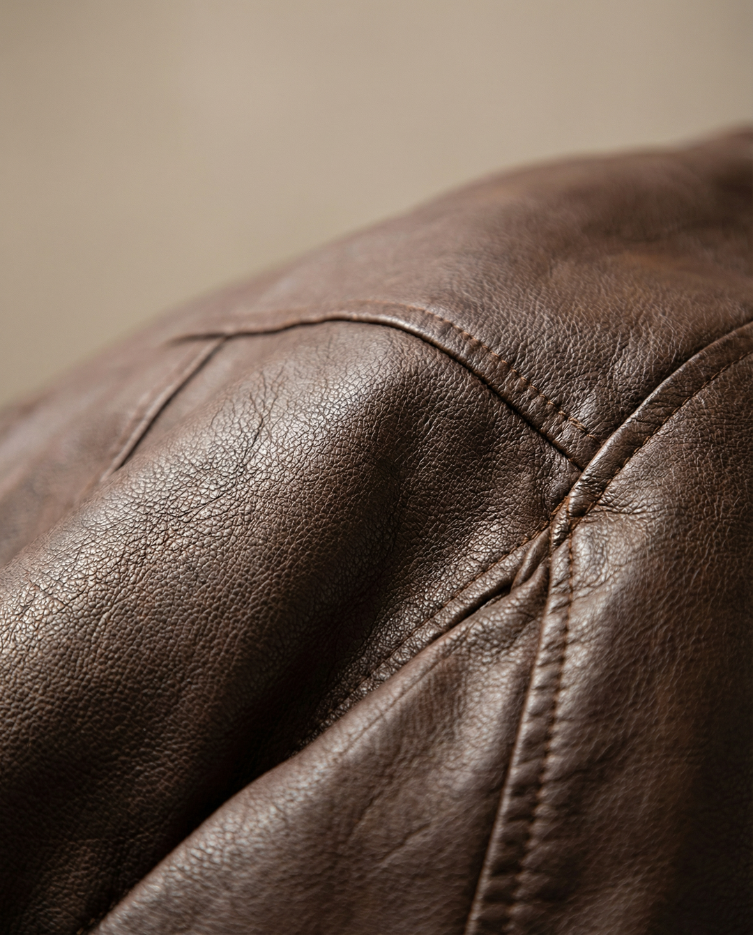 Close-up of a men's brown faux leather aviator jacket showcasing texture and zipper detail.