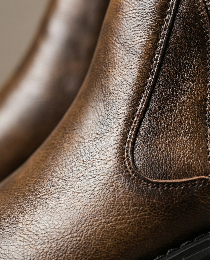 Close-up of the rich texture on brown full-grain leather men's ankle boots, highlighting the quality and craftsmanship