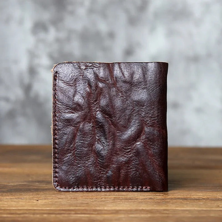 High-angle shot of a men's full-grain leather bi-fold wallet, emphasizing its compact and sleek form.
