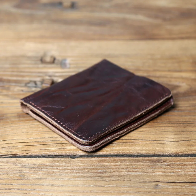 Detail of stitching on a men's full-grain leather bi-fold wallet, indicating quality craftsmanship.