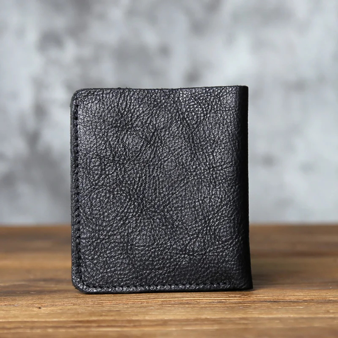 Men's full-grain leather bi-fold wallet on a wooden surface, highlighting its natural and rugged appeal.