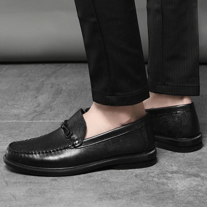 Close-up of a men's genuine leather loafer, showcasing the polished metal bit and stitching detail.