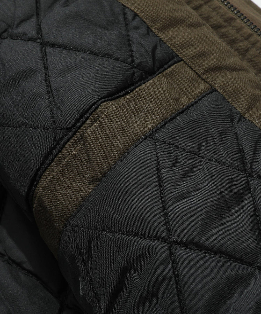 Close-up on the fabric texture of a men's utility field jacket and its quilted finish.