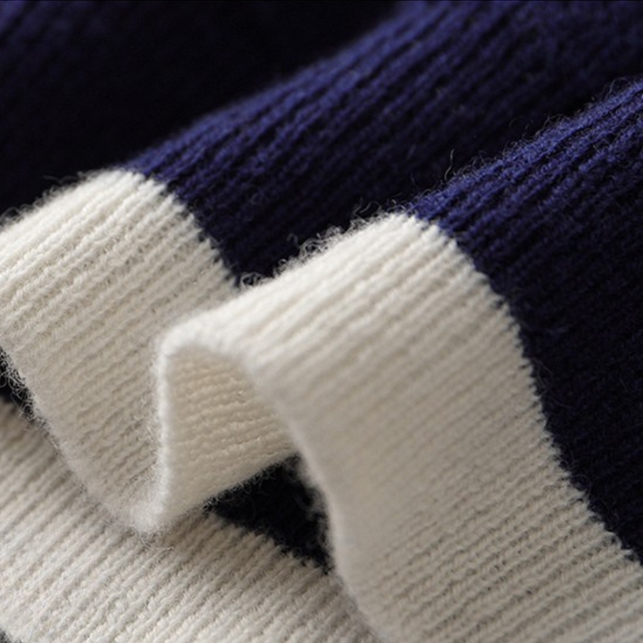 Detailed view of the ribbed cuffs and hem on a men's contrast stripe knit crewneck sweater.