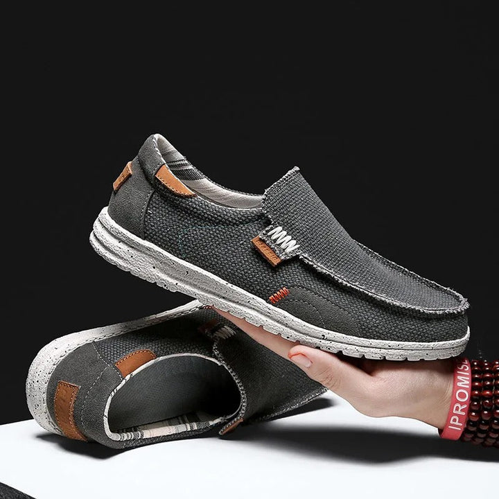 Men's gray canvas slip-on shoes paired with jeans, demonstrating casual style