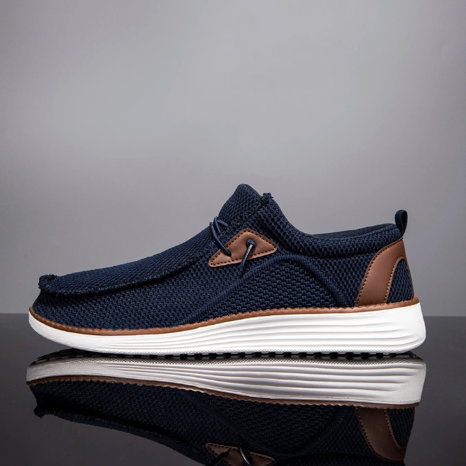 Hand holding a single lightweight woven loafer, emphasizing its airy feel and flexibility
