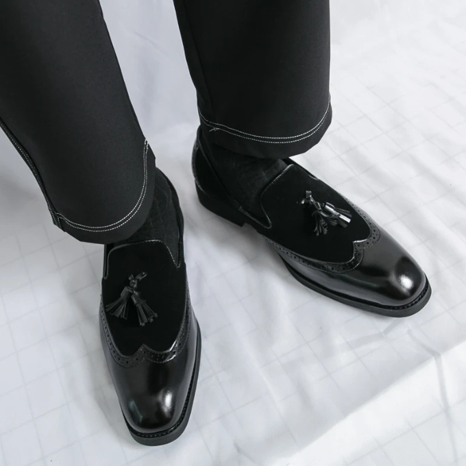 High-angle shot of luxurious men's formal shoes, black leather loafers with classic tassel design.