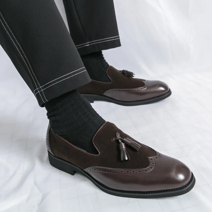 Men's formal footwear: black leather loafers with shiny finish and prominent tassel embellishments.