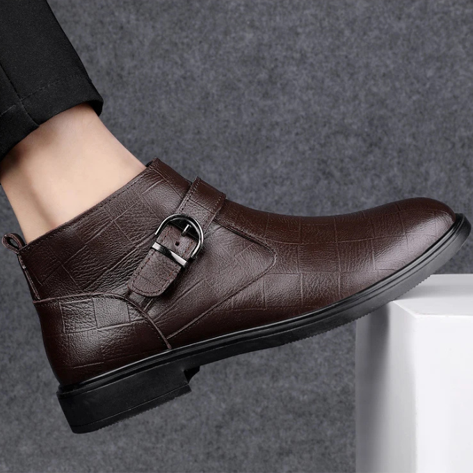 Close-up of the textured leather on men's luxury black ankle boots, showcasing durability.
