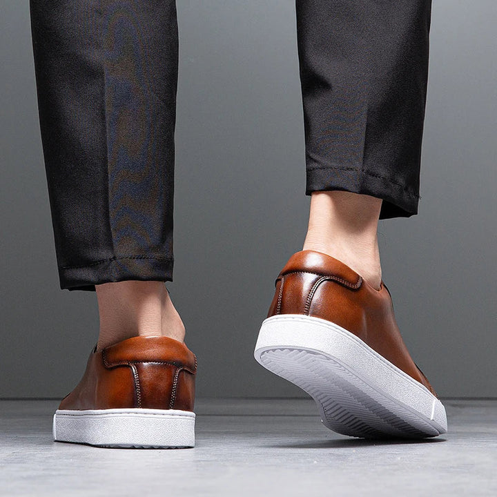 Man tying laces on men's genuine leather casual sneakers, comfy everyday shoes