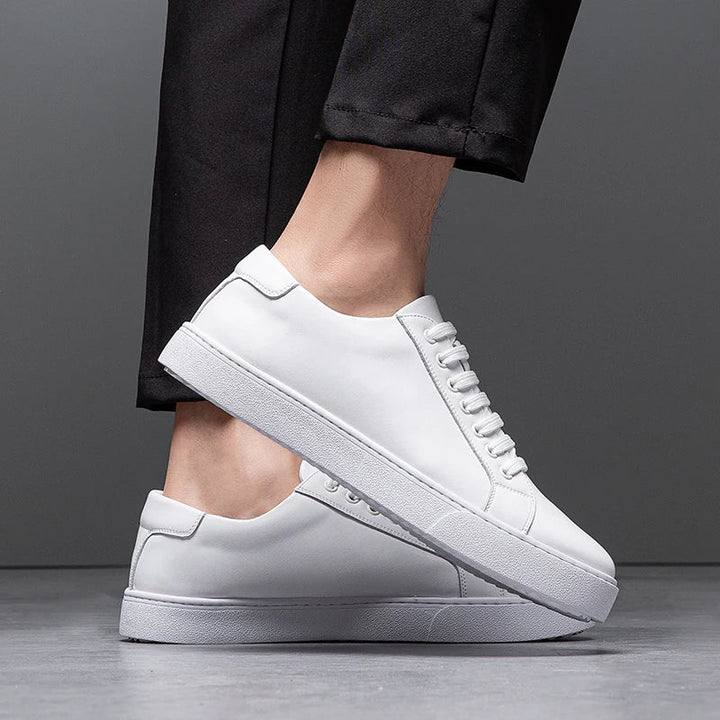 Pair of men's white leather sneakers on a concrete background, modern street style