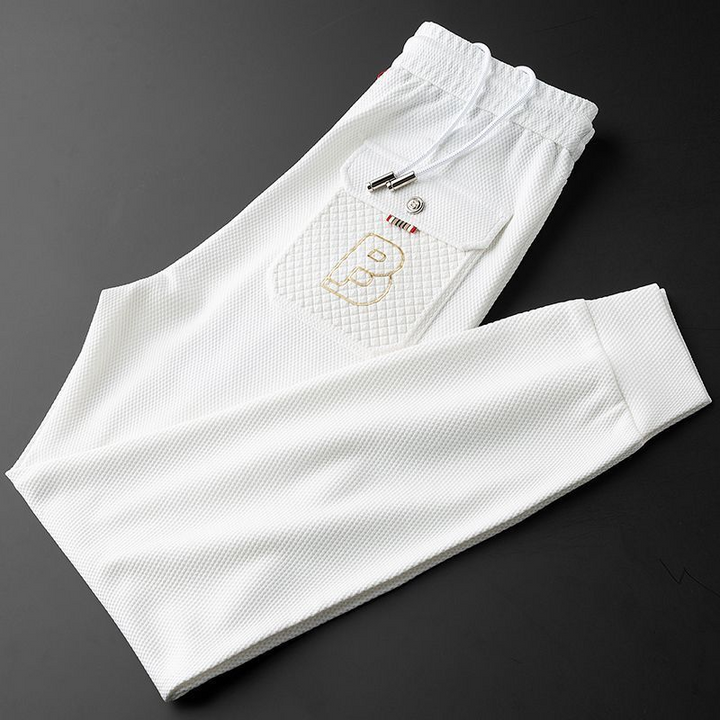 Drawstring waist and pockets of men's athletic tapered joggers, soft fabric texture visible.