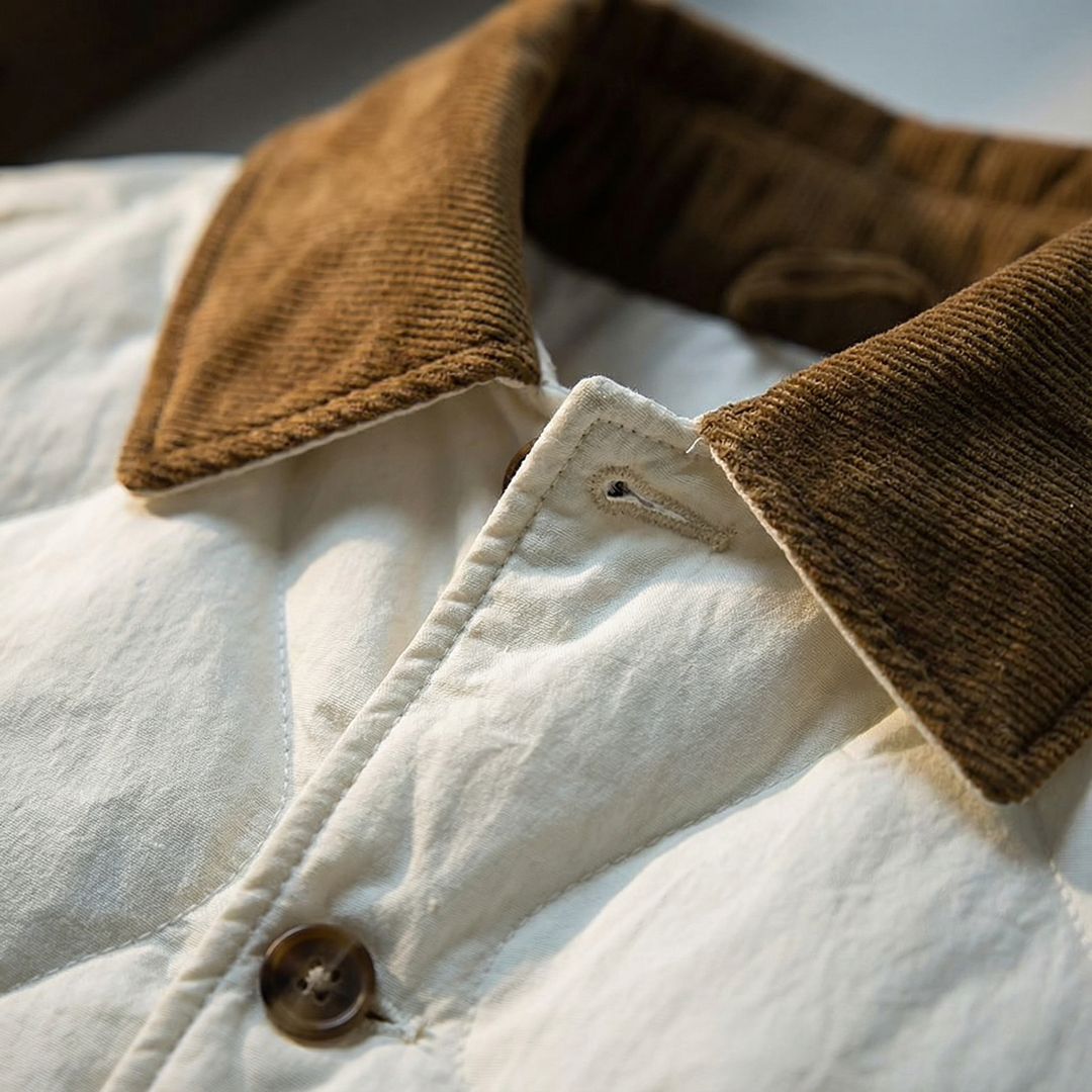 Detailed shot of the corduroy collar and snaps on a men's quilted cotton winter coat