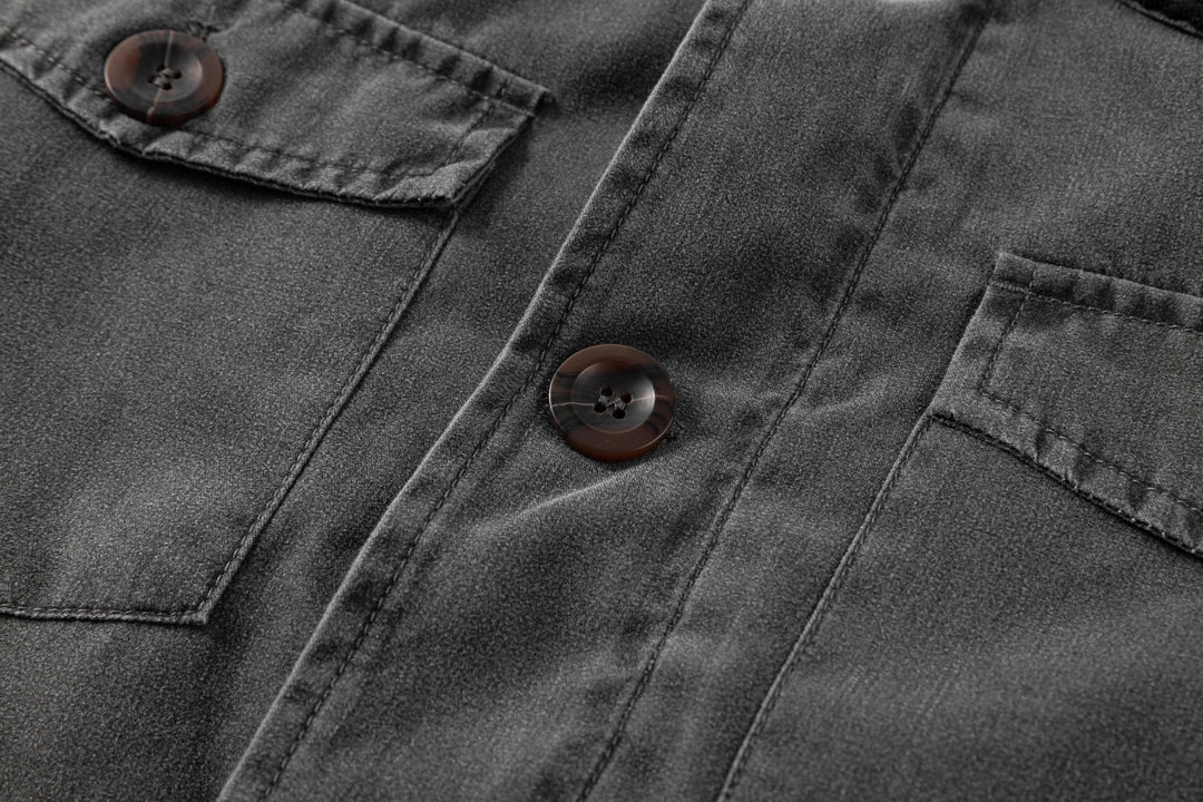 Close-up of the durable canvas fabric of the men's black jacket, with contrasting corduroy collar.