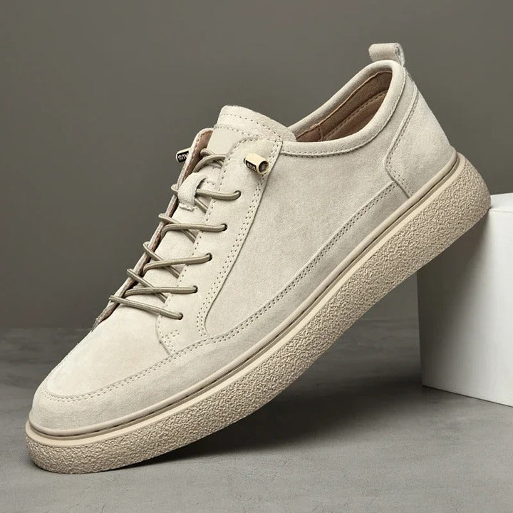 Close-up of a men's low-top suede sneaker in sand, highlighting texture and design.