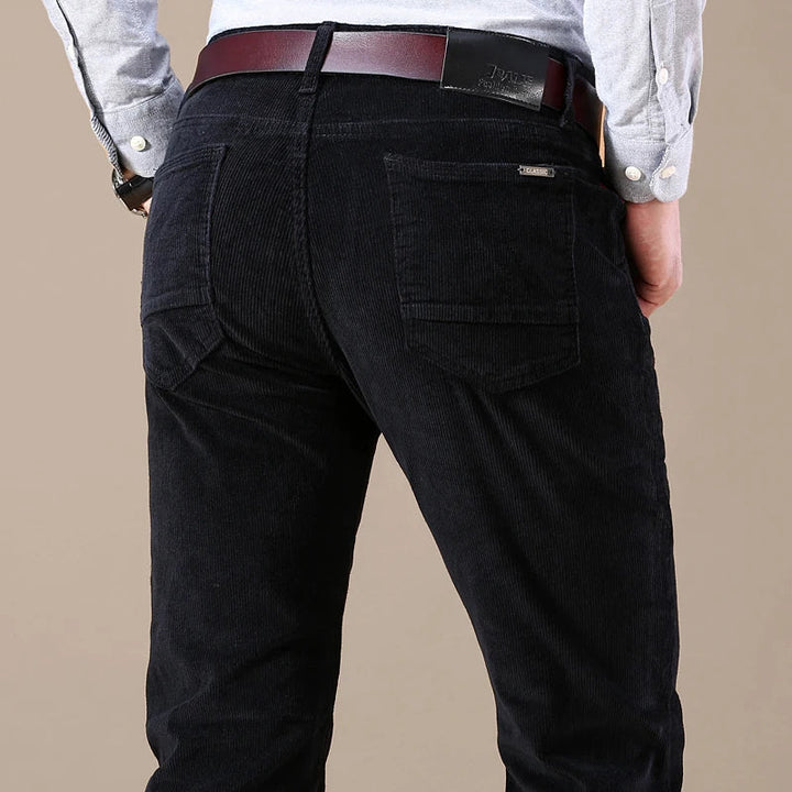 Close-up of ribbed corduroy fabric on men's tailored trousers, showcasing soft texture and quality.