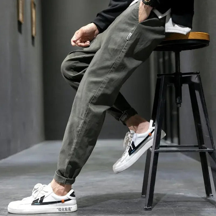 Stack of folded men's tapered joggers in various colors: black, gray, and navy for casual wear.