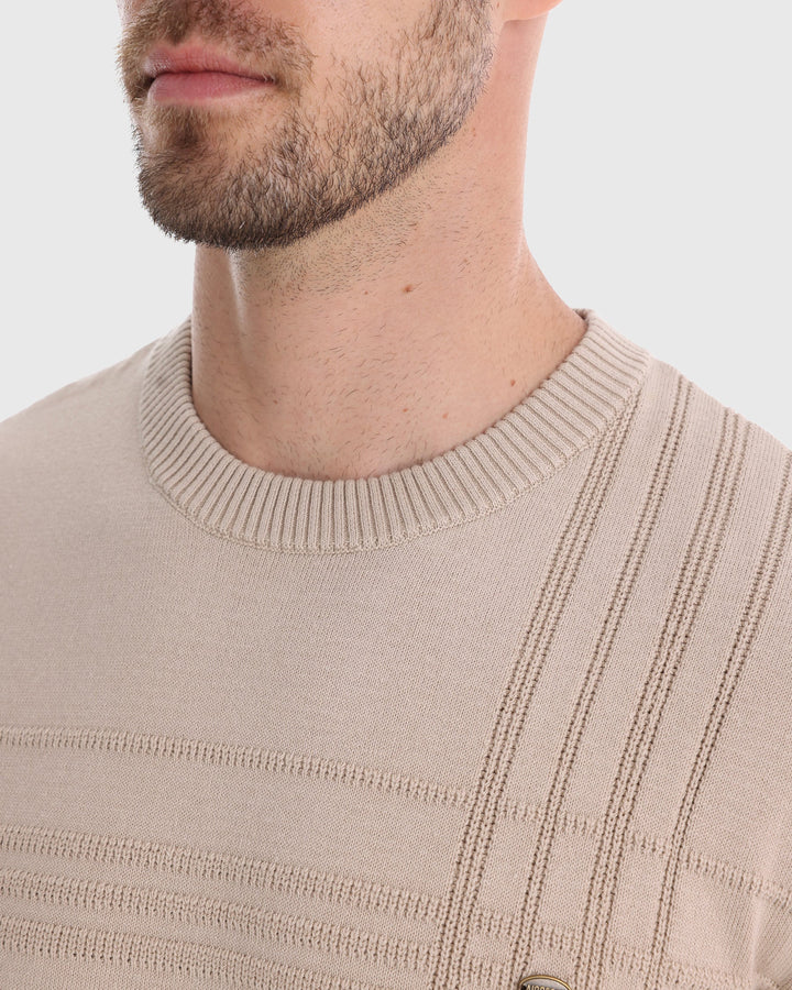 Man in a textured knit crew neck sweater, looking thoughtfully into the distance