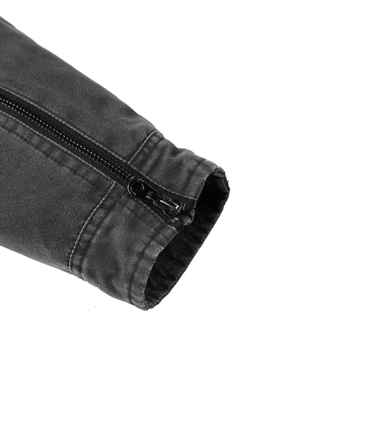 Close-up of the sturdy zipper and button details on a men's charcoal canvas jacket.