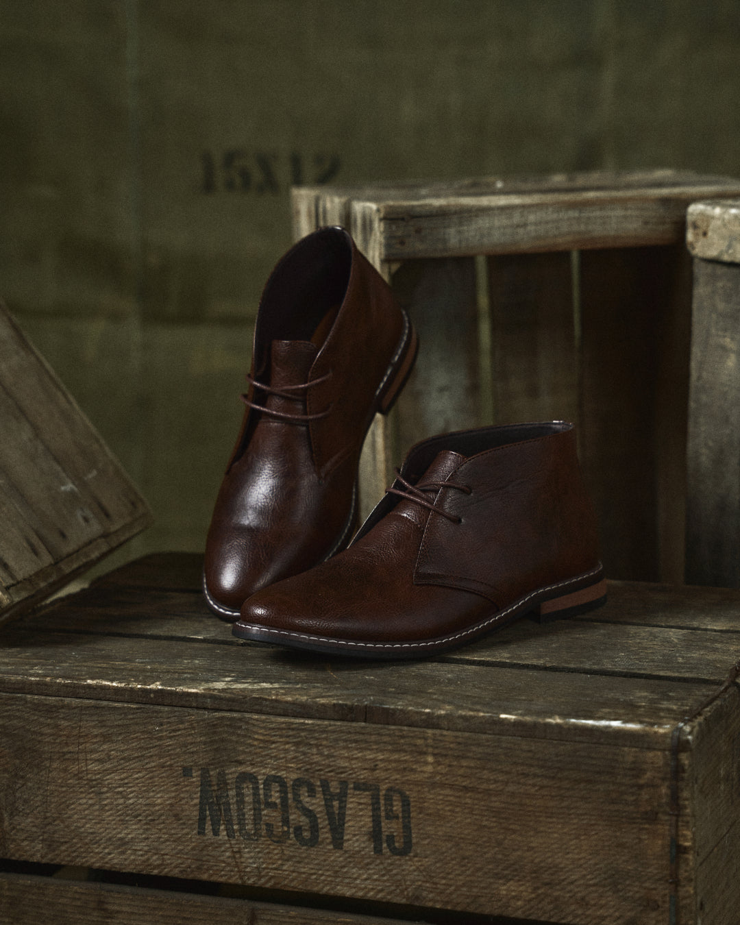 Rugged men's dark brown leather ankle boots, worn on a model, casual outfit, outdoor setting