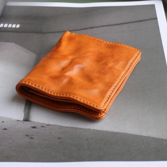 Open men's tri-fold leather wallet with multiple card slots and clear ID window visible