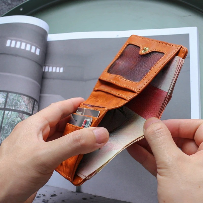 Men's full grain leather tri-fold wallet held in hand, demonstrating its comfortable fit