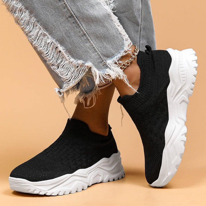 Top-down view of black & white everyday slip-on shoes, featuring orthopedic foot support