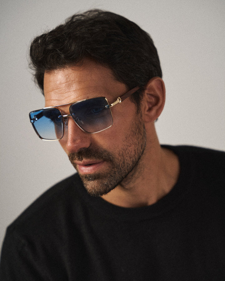Modern unisex square sunglasses featuring a striking gold frame & wood accents, stylish accessory.