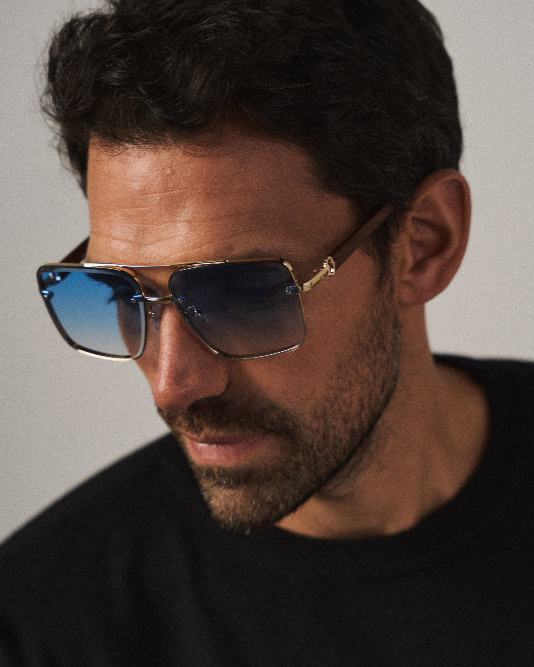 Close-up of bold square unisex sunglasses, highlighting the gold metallic detail & wood texture.