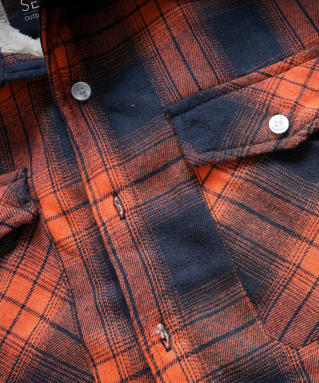 Detail shot of the buttons on a classic plaid flannel shirt jacket, unisex appeal.