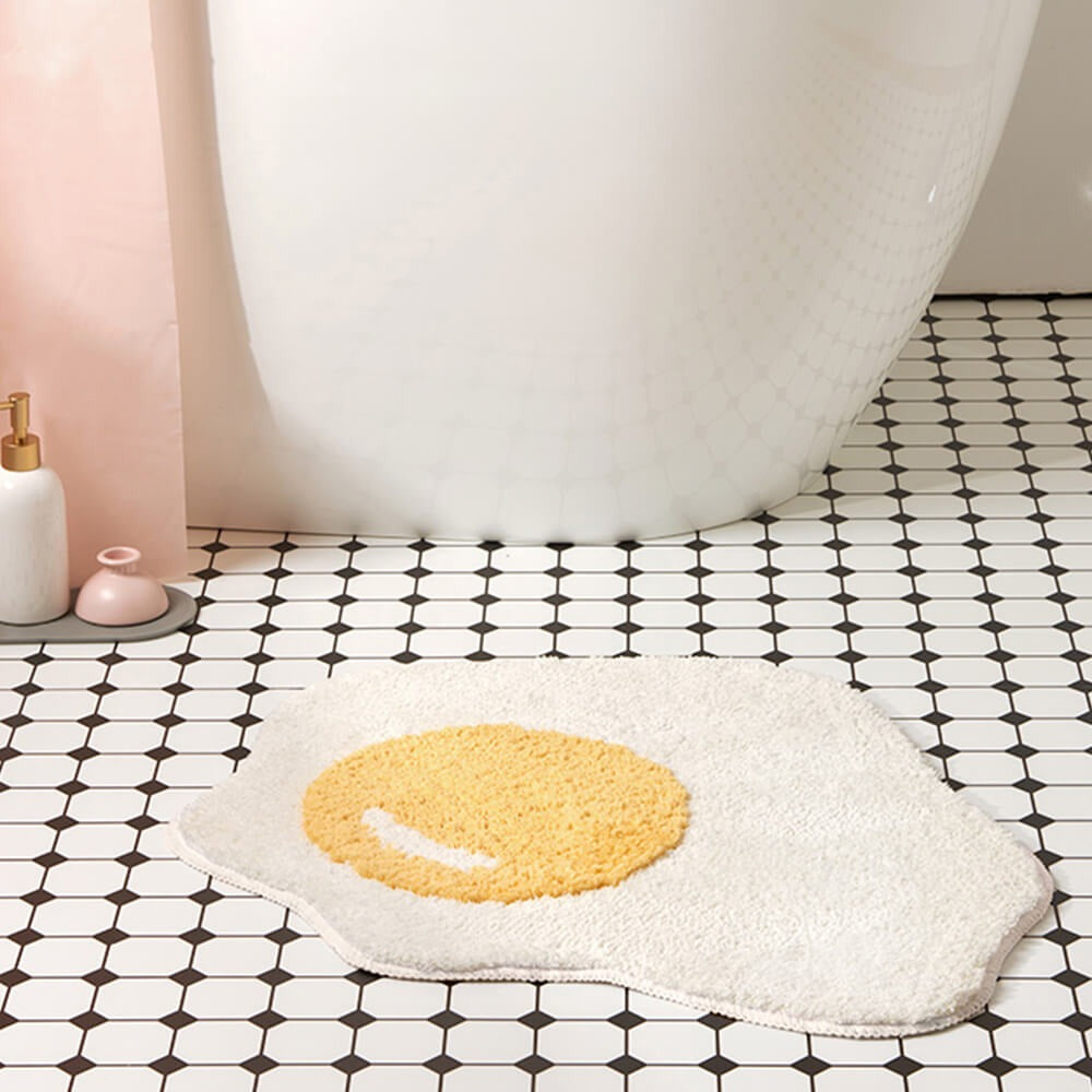 Unique fried egg bath mat, a soft shaggy rug for whimsical home decor. Absorbent, non-slip & machine washable.
