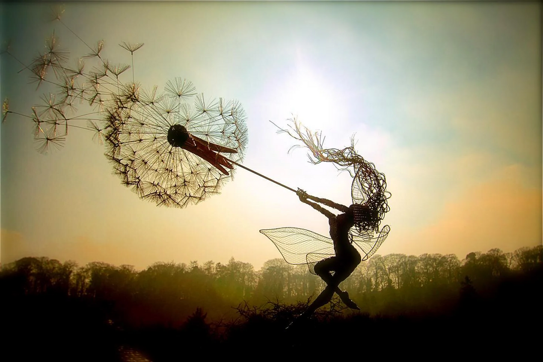 Whimsical metal fairy with lifelike dandelion stakes, ideal for enchanting garden decor, adding magic to outdoor spaces.