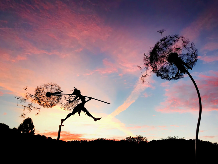 Whimsical metal fairy with lifelike dandelion stakes, ideal for enchanting garden decor, adding magic to outdoor spaces.
