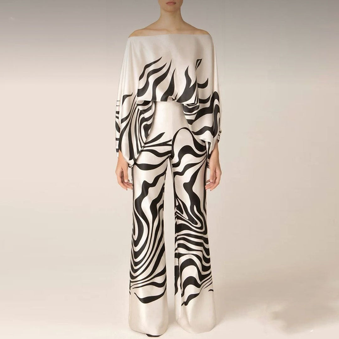 Full length view of a women's artistic printed two-piece set, with a one-shoulder top and elegant wide-leg pants.
