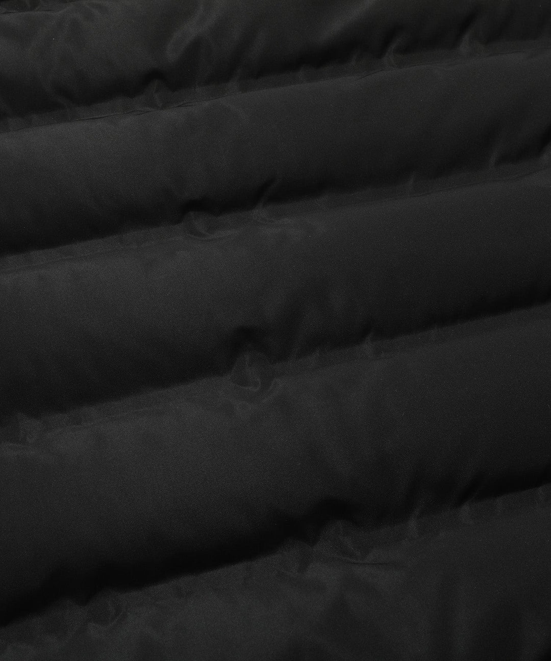 Close-up of the insulated material and stitching on a women's black hooded winter parka coat.