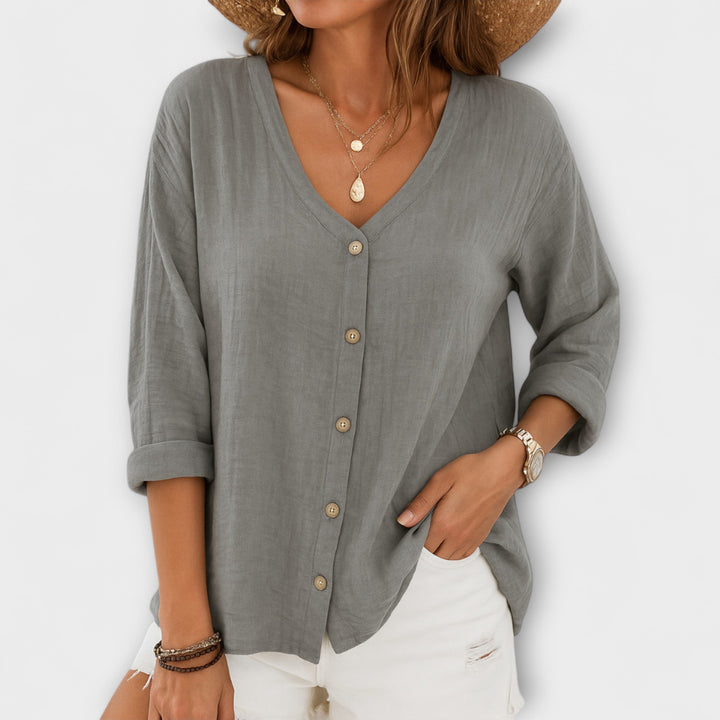 Stylish woman wearing a casual button-up blouse, relaxed fit, long sleeve. Versatile V-neck top for women's fashion.