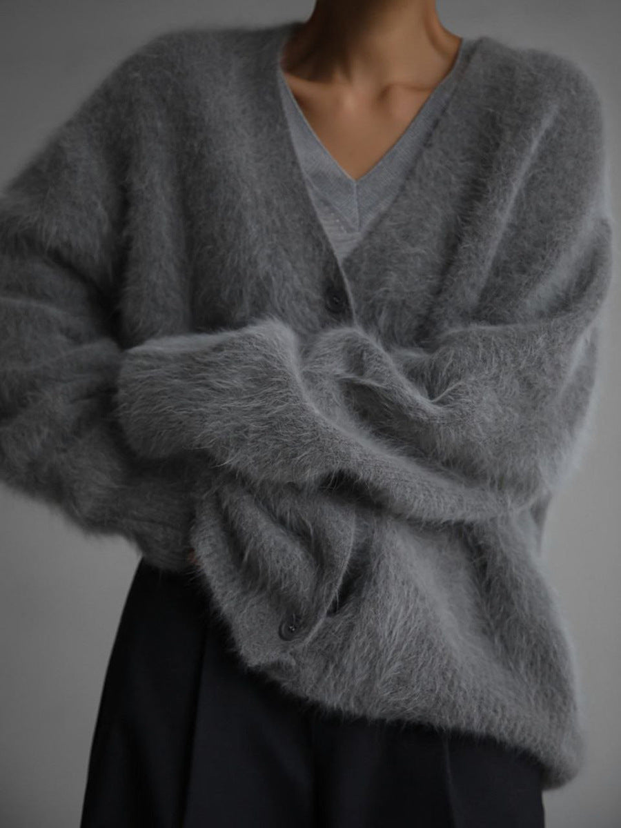 Lifestyle shot of a woman relaxing in a cozy knit oversized cardigan by a fireplace
