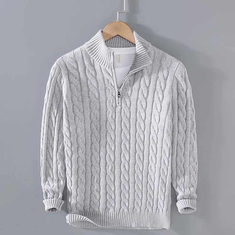 Close-up of the intricate cable knit pattern on a women's half-zip sweater in a light color.