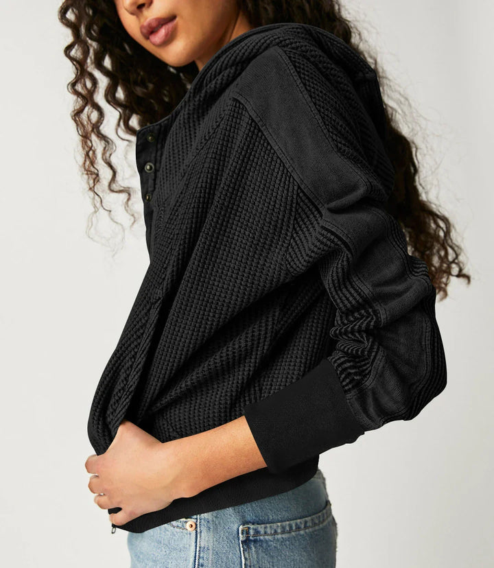 Close-up of the hemline of a women's cropped waffle-knit zip hoodie, modern style